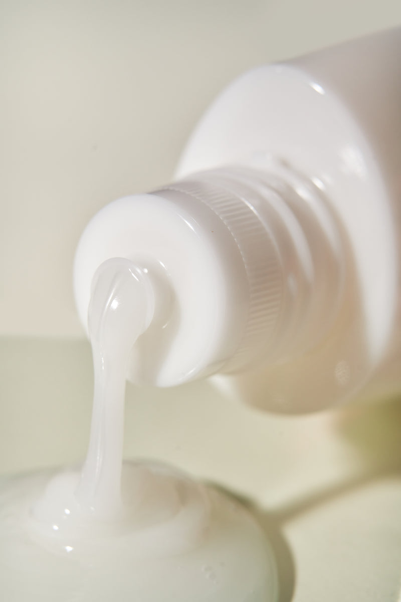 An up close image of Sekkisei Clear Wellness Softening Milk with the product coming out of packaging. 